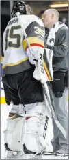  ?? Kathy Willens ?? The Associated Press A trainer looks at Golden Knights goalie Oscar Dansk during the second period Monday. Dansk left with an apparent lower-body injury, meaning Vegas had to use its fourth goalie just 10 games into the franchise’s history.