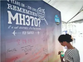  ?? VINCENT THIAN/AP ?? A girl writes a condolence message March 3 in Malaysia to mark a Day of Remembranc­e for MH370, the flight that vanished in 2014.