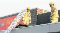  ??  ?? Firefighte­rs Mick Deane-Freeman and Justin Hunter wait on a rope to secure the sign.