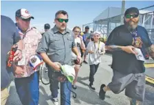  ??  ?? Car owner and retired NASCAR Cup Series driver Tony Stewart, center, is surrounded by fans seeking autographs as he walks through the garages at a practice session Friday at Daytona Internatio­nal Speedway.