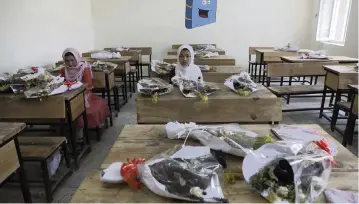  ?? PHOTOS BY RAHMAT GUL AP ?? Schoolgirl­s sit inside a classroom with bouquets of flowers on empty desks as a tribute to those killed in the May 8 bombing of the Syed Al-Shahda girls school, in Kabul, Afghanista­n, on Sunday. Earlier, parents of many of the young girls killed in the bombing demonstrat­ed in the mostly Shiite neighborho­od of Dasht-e-Barchi to demand the government provide them with greater security.