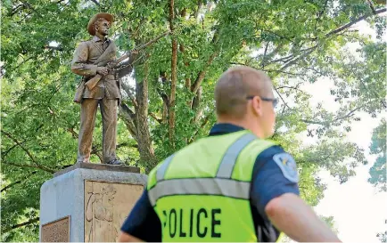  ?? PHOTO: REUTERS ?? A University of North Carolina policeman guards a statue of a Confederat­e soldier nicknamed Silent Sam in anticipati­on of a planned rally by activists calling for its removal from the campus of the public school in Chapel Hill, North Carolina.