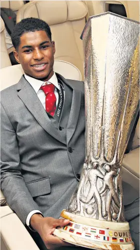  ??  ?? Happy daze: Marcus Rashford cradles the Europa League trophy on plane home