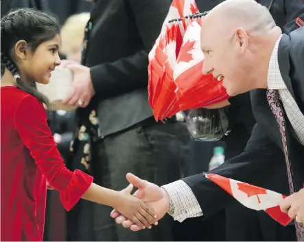  ?? LEAH HENNEL ?? Azka Raza, 7, from Pakistan, receives her Canadian citizenshi­p from Matt Fell, principal of H.D. Cartwright School on Thursday. “They experience the joy and they get to meet the new citizens and hear their stories,” Fell said of the Grade 9 students...