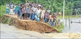  ?? PTI PHOTO ?? Villagers look on as a part of an embankment is washed away by flood waters at Nam Doboka village in Hojai district of Assam on Friday.