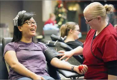  ?? PHOTO BY AMERICAN RED CROSS ?? A Red Cross collection staff member prepares to take a blood donation from a donor.