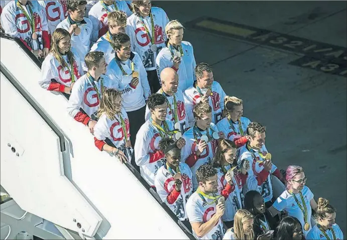  ?? CARL COURT / GETTY ?? L’arribada triomfal a l’aeroport de Heathrow dels esportiste­s anglesos, que somriuen mostrant les seves medalles