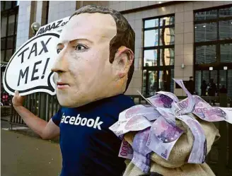  ??  ?? Ativista com máscara de Zuckerberg protesta contra o Facebook em Bruxelas