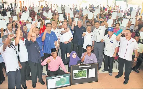  ??  ?? Awang Tengah (standing front, fifth right) in a group photo with the recipients of land titles at Dewan Sentosa of Putra Sentosa Camp in Sematan. He is flanked by Wan Junaidi on his right and Naroden.
