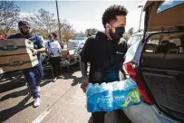  ??  ?? Trae Tha Truth, left, and DJ Mr. Rogers, of The Relief Gang, hand out food and water during a distributi­on Tuesday.