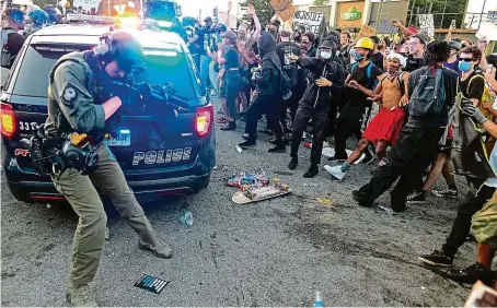  ?? FOTO ČTK/AP ?? Napětí v Atlantě.
Policisté uklidňují rozjitřeno­u situaci před restaurací řetězce Wendy’s, kde zahynul Rayshard Brooks. Podnik v sobotu v noci shořel.