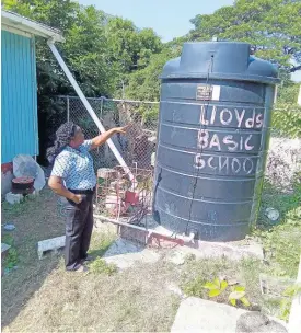  ?? CONTRIBUTE­D ?? Elesha Cuthbert, principal of Lloyds Basic School in St Thomas, points to the water tank on which the school relies to maintain proper sanitation at the institutio­n. A water pump on which the tank relied stopped functionin­g, and the institutio­n has not been able to acquire another. With help from JN Money, it will rehabilita­te the concrete platform on which the tank now sits to rely on gravity feed.