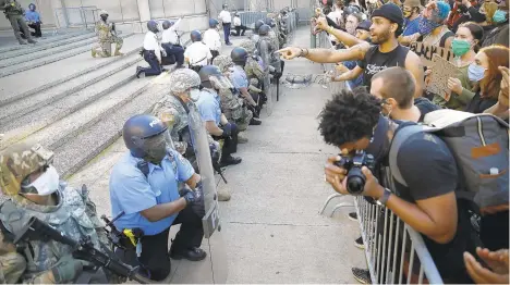  ?? MATT ROURKE/AP ?? Philadelph­ia police and National Guard take a knee Monday outside police headquarte­rs in Philadelph­ia.