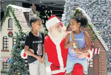  ?? Picture: FREDLIN ADRIAAN ?? THE WINNER: FESTIVE SMILES: Santa Hugh Davidson listens to the Christmas wish-list of twins Tyrone and Tarryn Human, 8, at Baywest Mall