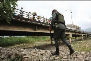  ?? AP/FERNANDO VERGARA ?? A police officer in La Parada, Colombia, patrols Tuesday near a bridge that connects Colombia and Venezuela.