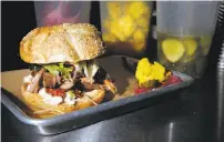  ??  ?? Jeff Mason, top, at work at his Pal’s Takeaway pop-up. Above: Ginger lime-basted rotisserie lamb on a sesame roll with roasted Jimmy Nardello peppers, balsamic figs, feta, papadum chips and heirloom tomatoes.