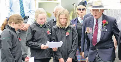  ?? PHOTO: RICHARD DAVISON ?? In remembranc­e . . . West Otago RSA senior member Bill Roulston (99) reads a section of For the Fallen with West Otago Rural Kids members (from left) Isla Ottrey, PeytonRose Young and Jessie Lindale (all 10), during yesterday’s Armistice Day service in Tapanui.