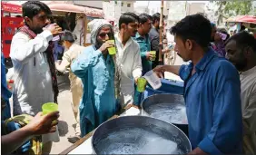  ?? ?? Refresh… People drink water being distribute­d by volunteers along a street during a heatwave in Jacobabad, Pakistan.