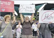  ?? HYOSUB SHIN PHOTOS / HSHIN@AJC.COM ?? Mitzi Mills (center) holds a sign along with other protesters as they gather at Centennial Olympic Park before the Take Down White Supremacy March on Saturday.