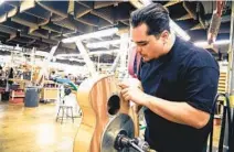  ??  ?? At Taylor Guitars’ El Cajon facility, Clinton Jackson works on a guitar made out of urban wood.