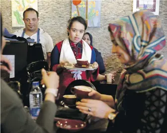  ??  ?? Staffer Melika Aghaei, 14, serves coffee at the Downtism Café in Tehran.