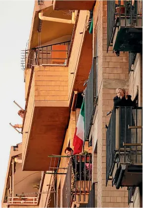  ??  ?? Quarantine­d people in Rome watch a flash mob from their balconies.
