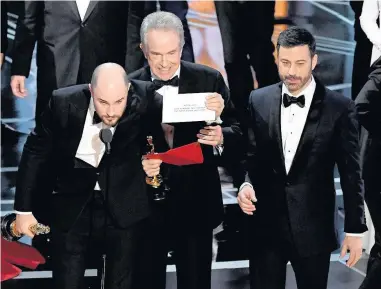  ??  ?? > La La Land producer Jordan Horowitz holds up the winner card reading actual Best Picture winner Moonlight with actor Warren Beatty and host Jimmy Kimmel at this year’s Oscars