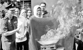  ??  ?? Zuraida putting out the fire using a fireproof cloth at a Fire Safety Campaign and Launch of the JBPM Suri Programme in Penang yesterday.