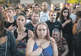  ?? Kent Nishimura Los Angeles Times ?? AMBER BRUCE, 23, center, stands for the national anthem with others attending a candleligh­t vigil at Gilroy City Hall on July 29, the day after the shooting.