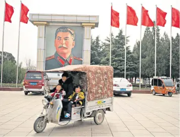  ??  ?? A vehicle passes Stalin’s portrait in Nanjie, central China. Wang Hongbin, left, party secretary and leader of the village in the Henan province since 1977