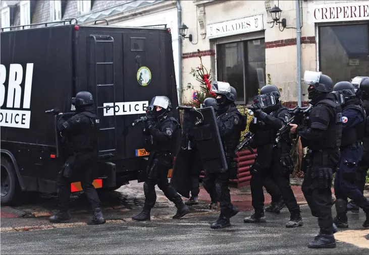 ??  ?? Armed presence: Riot police hunting for the Al Qaeda killers patrol the streets of Abbaye de Longpont, a village of 00 people north of Paris, yesterday