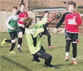 ??  ?? A Flixton under-13s man wins an aerial battle during their potentiall­y title-winning victory against Burlington Jackdaws (above left), while the Jackdaws keeper is forced into action (above right)
Pictures: Steve Lilly