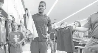  ?? Steve Gonzales / Houston Chronicle ?? Andre Johnson and children on shopping sprees go hand in hand in Houston, and Thursday was no different for the former Texans receiver at this back-to-school event featuring 30 kids from area Boys and Girls Clubs with $100 gift cards. For more, go to...