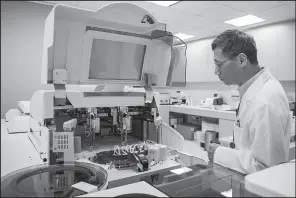  ?? Bloomberg News/XAUME OLLEROS ?? A technician inspects a blood analyzer in the Roche Holding AG diagnostic lab in Hong Kong in this file photo. Of the seven biosimilar drugs the FDA has cleared since 2015, including a version of Roche’s Avastin cancer treatment, only three are...