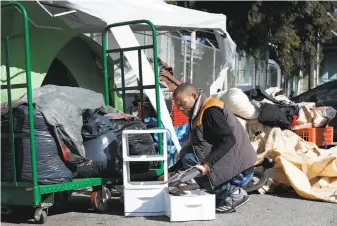  ?? Paul Chinn / The Chronicle ?? Ricky Walker reorganize­s his belongings at a homeless camp on Vermont Street, a block from where he and others had been camping before a sweep Thursday.