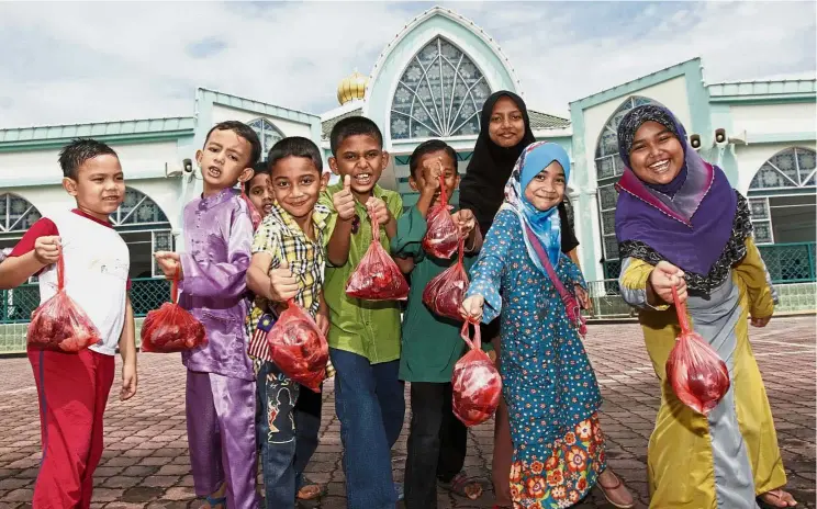  ?? — LIM BENG TATT/ The Star ?? Lots to take home: Children posing with the packets of meat they received at Masjid Al-Malik Khalid in Universiti Sains Malaysia, Minden, Penang during Hari Raya Haji.