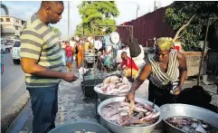  ?? DIEU NALIO CHERY / THE ASSOCIATED PRESS ?? A fish vendor picks out fish for her client at the biggest fish market in Port-au-Prince, Haiti.