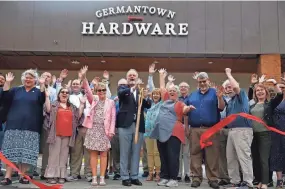  ?? PHOTOS BY CHRISTINE TANNOUS/THE COMMERCIAL APPEAL ?? John Sieggreen, president of Central Network Retail Group, cuts the ribbon as other officials pose with their hands up during a ceremony Tuesday at Germantown Hardware. Renovation­s at the store include an expansion of the size as well as new products and services, such as an outdoor plant space.