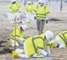  ?? RINGO H.W. CHIU/AP ?? Workers in protective suits clean the contaminat­ed beach in Newport Beach, Calif., last week.