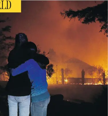  ?? JEFF CHIU / THE ASSOCIATED PRESS ?? Two women hug as they watch houses burn in Santa Rosa, Calif., as dozens of wildfires swept through the northern part of the state on Monday.