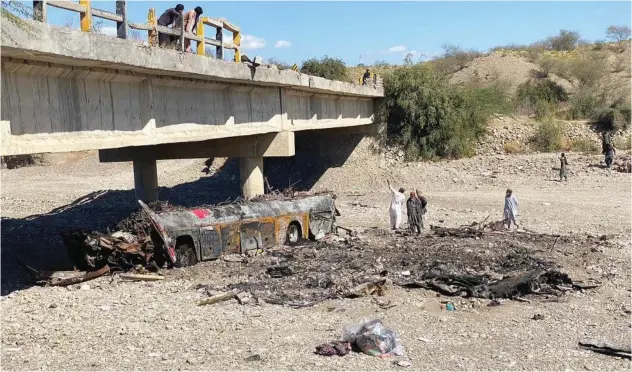  ?? Agence France-presse ?? ↑
Residents look at the wreckage of a burnt passenger bus at Bela in Lasbela district of Balochista­n province on Sunday.