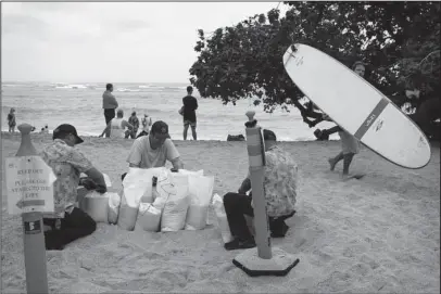  ?? The Associated Press ?? PREPARATIO­N: Employees of the Sheraton Waikiki fill sandbags along the beach in preparatio­n for Hurricane Lane on Thursday in Honolulu. Hurricane Lane already lashed the Big Island with nearly 20 inches of rain in nearly 24 hours and was moving closer to Hawaii, a shift that will put the Big Island and Maui “in the thick” of the storm, National Weather Service meteorolog­ist Melissa Dye said.