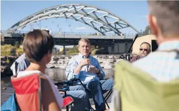  ?? KEVIN MOHATT/THE NEW YORK TIMES ?? Sen. Michael Bennet, D-Colo., speaks with community leaders Aug. 24 on the Platte River in Denver. Bennet promoted a budget bill that will include $60 billion to protect Colorado’s forests and watershed.