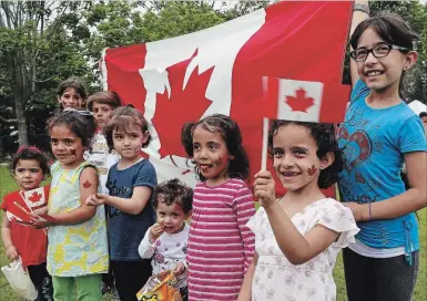  ?? CLIFFORD SKARSTEDT EXAMINER ?? Children gather for a photo with the Canadian flag during the annual Multicultu­ral Canada Day Festival on July 1, 2017 at Del Crary Park .