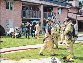  ?? BOB TYMCZYSZYN TORSTAR ?? St.Catharines firefighte­rs had to help a woman from a balcony at 99 Scott St. after a fire in the building Friday.