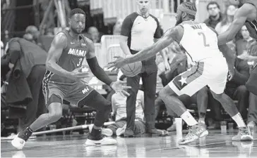  ?? NICK WASS/ASSOCIATED PRESS ?? Wizards guard John Wall, right, and Heat guard Dwyane Wade pursue the ball during the first half Thursday night.