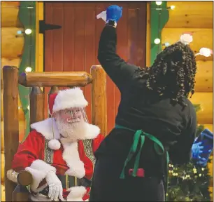  ?? (AP/Seth Wenig) ?? LaToya Booker cleans a transparen­t barrier between visitors for Santa at a Bass Pro Shop in Bridgeport, Conn.