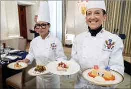  ?? ANDREW HARNIK — THE ASSOCIATED PRESS ?? White House executive chef Cris Comerford, left, and executive pastry chef Susie Morrison hold dishes Wednesday during a preview for the state dinner at which President Joe Biden will host French President Emmanuel Macron at the White House on Thursday.