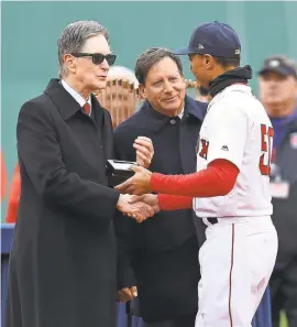  ??  ?? John Henry awards Mookie Betts his 2018 World Series ring during the Red Sox’s 2019 home opener.