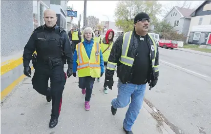  ?? KEVIN KING ?? Winnipeg police Const. Jeff Boehm, left, walks with a group lead by Bear Clan Patrol organizer James Favel. Since 2015, Favel and his team have evolved the patrol’s mandate — upgrading to become a welcome wagon, resource service, cleanup crew, conflict...